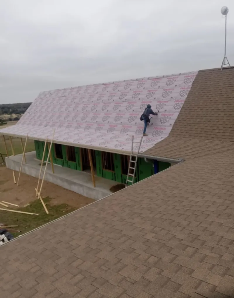 Worker preparing underlayment for a metal roof installation in El Granada